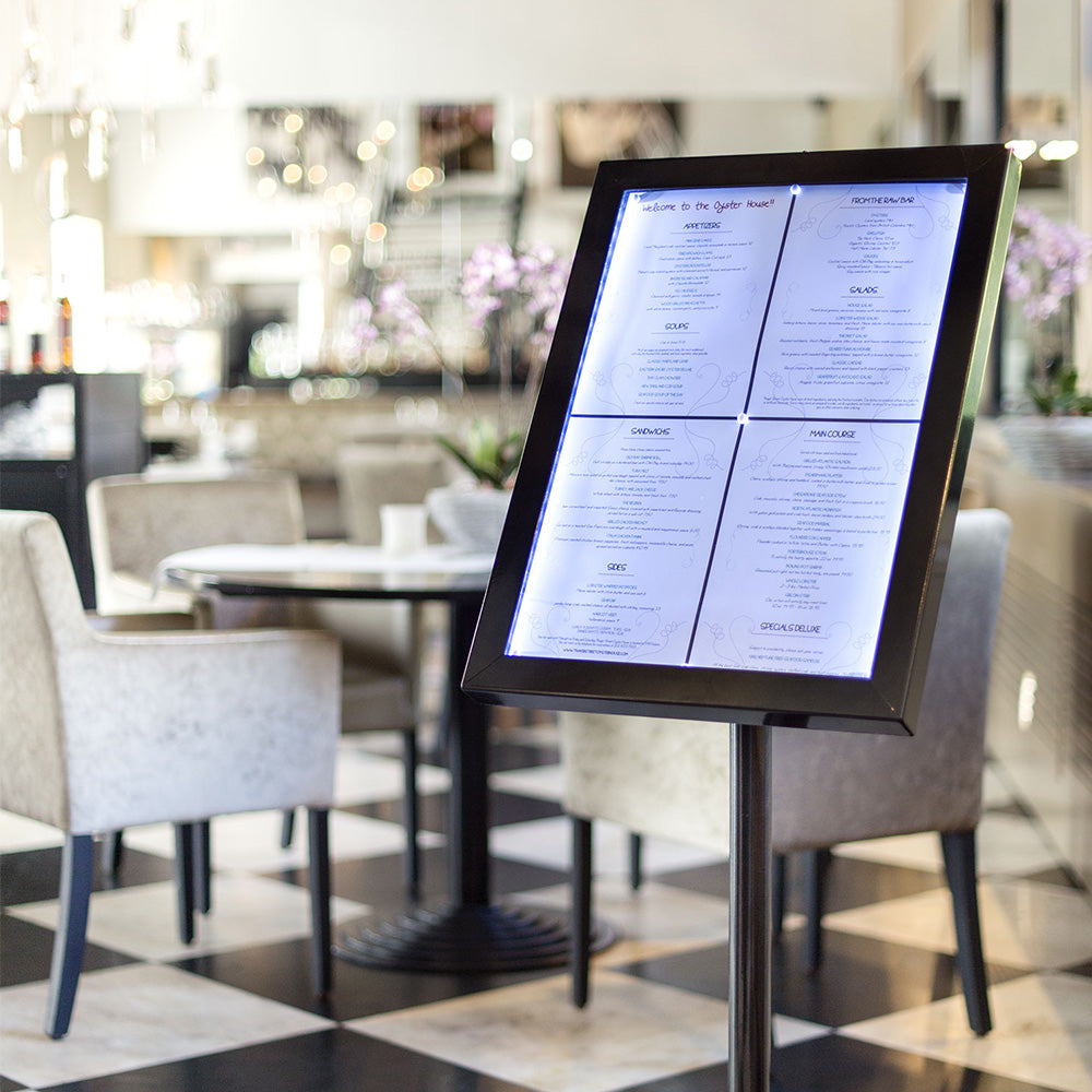 A stylish and secure set of four A4 tamperproof LED restaurant menu display boards in black, offering both floor-standing and wall-mounted options for versatile presentation.
