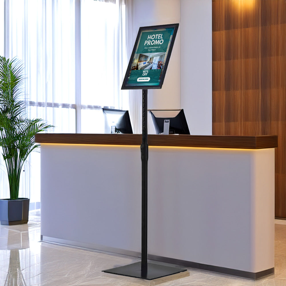 Floor-standing black A4 poster display stand with a mitred snap frame, 360-degree rotation, and a sturdy square base.
